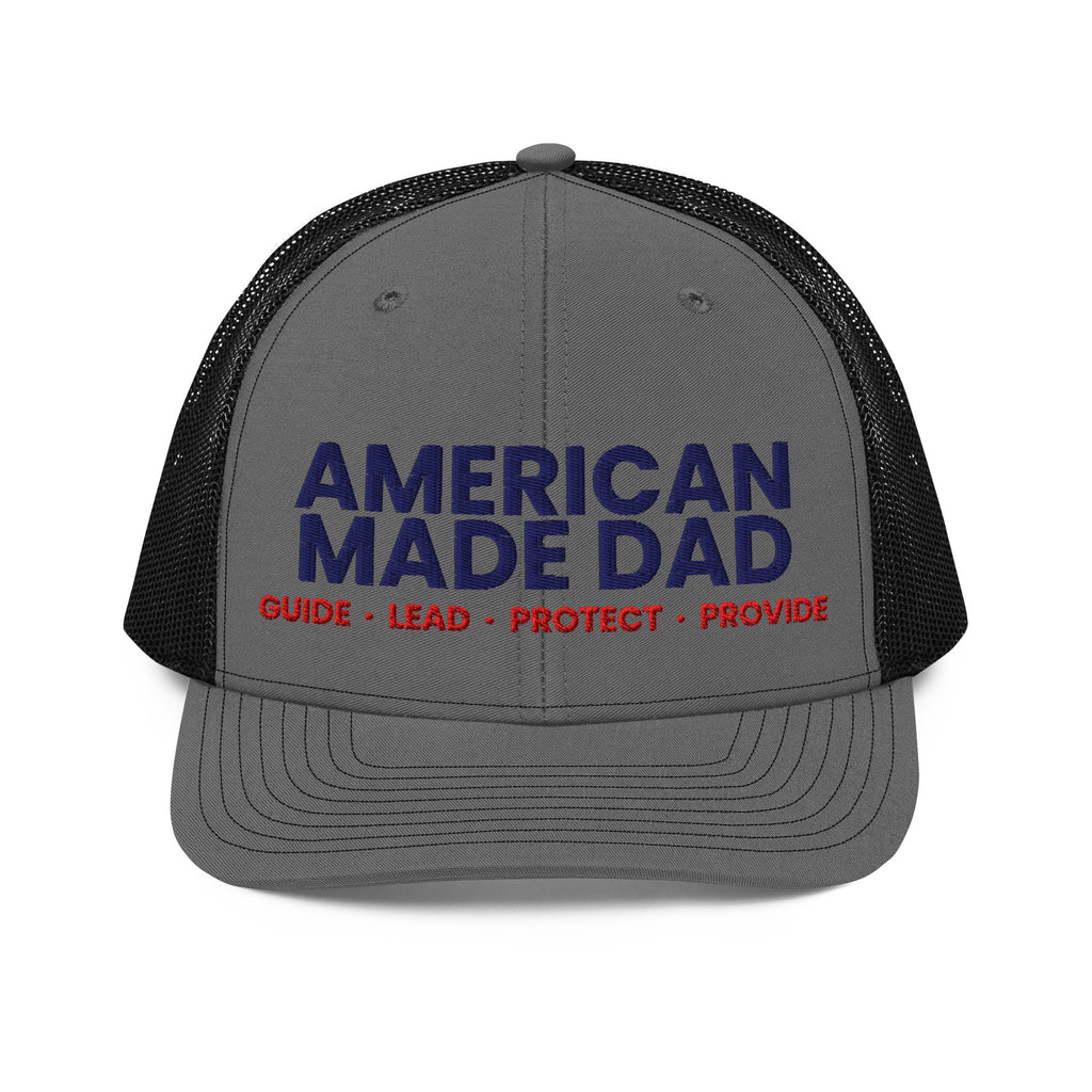 Front of a charcoal and black snapback trucker cap with the embroidered American Made Dad compass