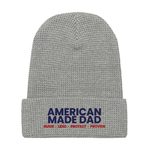 Front of a heather grey waffle knit beanie with the embroidered American Made Dad compass